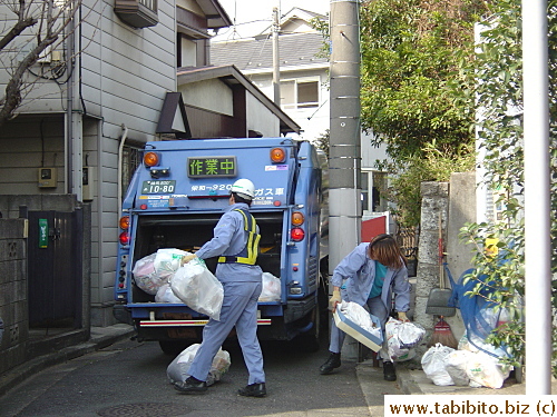  Garbage workers hard at work, the one on the right is a bit sloppy with his uniform