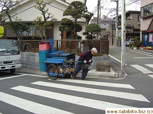 A roasted sweet potato vendor lugging his cart up an incline