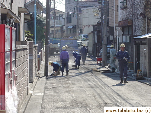 Road workers sweeping the ground with straw brooms