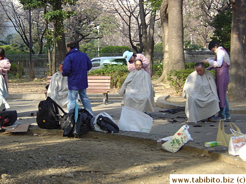 Volunteers giving homeless men haircut