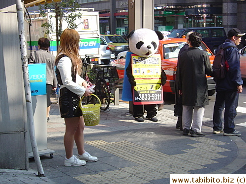 Girl giving away free tissues and the man on the right is dressed up as a panda advertises for a shop