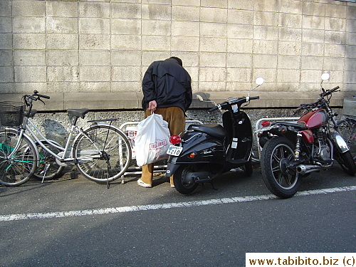 Man peeing on the street in broad daylight, look between his legs