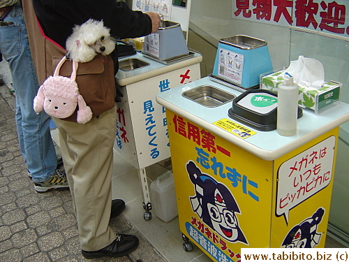 A grown man with a childish bag and a doggie, and they don't look out of place at all in a society overfilled with cute things. Btw he's cleaning his glasses in the machine and everything he needs to complete the process is provided, courtesy of the glass shop