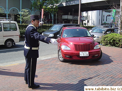Guard outside a parking garage directing human and car traffic