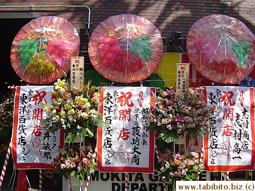 These big banners with the round flower board things are often seen in front of stores on the grand opening day such as this one