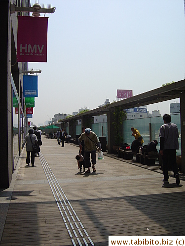 Board walk outside Takashimaya dept Store, Shinjuku.  Many benches are occupied by homeless people