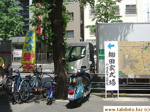 Another sign that tells people where the funeral's being held. (The blue, red and yellow banner advertises for a comic books café)