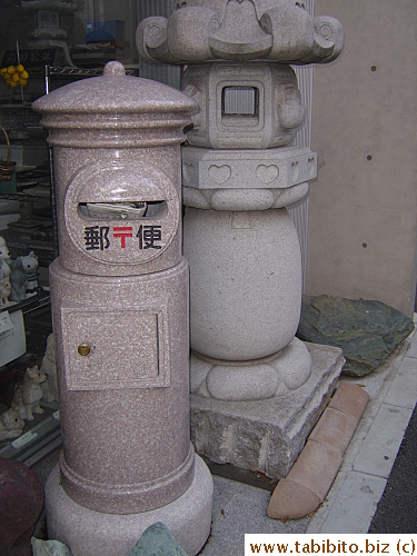 A stone postbox for sale in this store.  Someone wanted to mail a newspaper