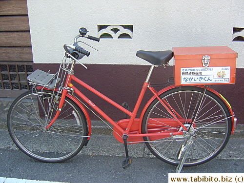 This postal bicycle is parked in front of this house.  The postman must have gone inside to deliver something