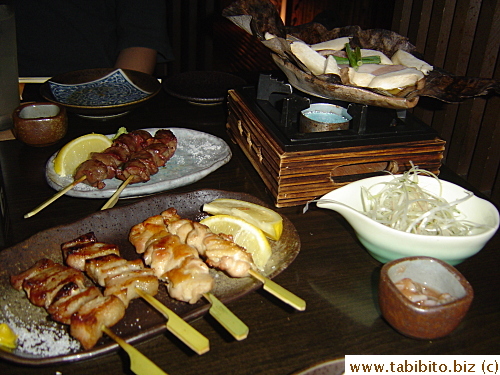 Grilled chicken on sticks and mushroom and pork in miso cooked on a dried leaf over fire