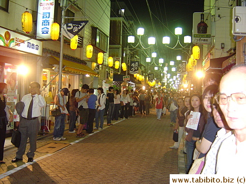 Lots of people line up the shopping street to wait for the parade to come