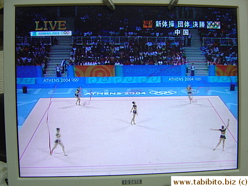 Chinese rythmic gymnasts in action. Their colorful costumes did not have enough purple in them to match the purple ribbons. They did not get any medals in the end