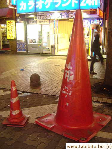 In a side street in Shinjuku. We found a normal-sized traffic cone next to a humongous one