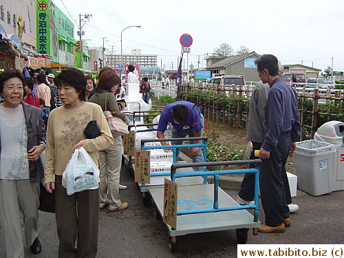 Trolleys from different tour groups line up in front of the fish shop for people to put their purchase on them. Staff will then transfer the goods to the corresponding buses