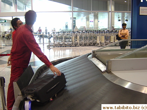 This staff at KL airport is to straighten all bags that land on to the baggage carousel to a horizontal position