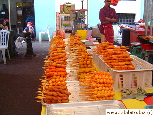 This food stall sells fried food on a stick.  They are all one color, pretty strange