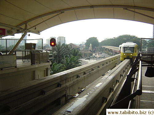 A yellow monorail train pulling up the platform