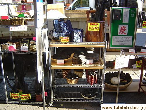 Expensive charcoal displayed on the street with no one to watch over it.  The green sign on the right says: If you wish to buy any of the charcoal, press the button please.  