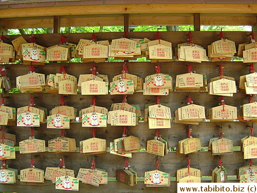 Wooden plaques on which people write their wishes also feature the beckoning cat
