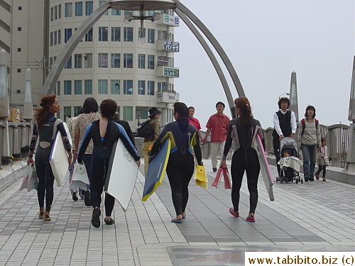 Young people in wet suits heading towards the beach