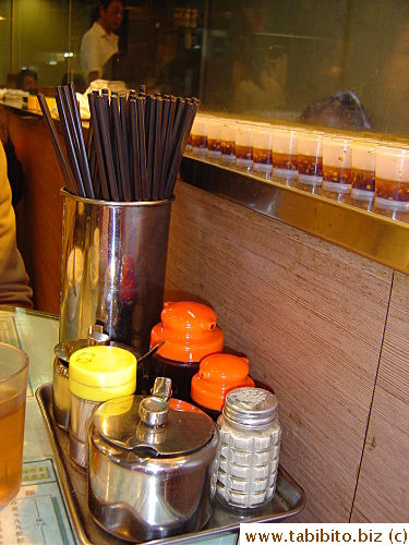 Typical tray of condiments and chopsticks on the tables of a diner. The single-size servings of chili oil on the window sill are not just for decoration