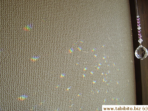 Swinging crystal casts its pretty colors on the wall