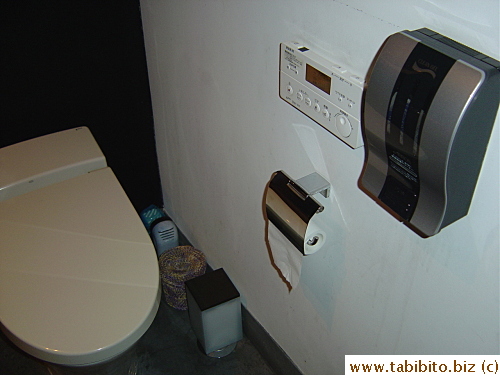 The toilet seat cover lifts up automatically when you stand in front of it. I didn't spend long enough time in the bathroom to figure out what that gray box is for