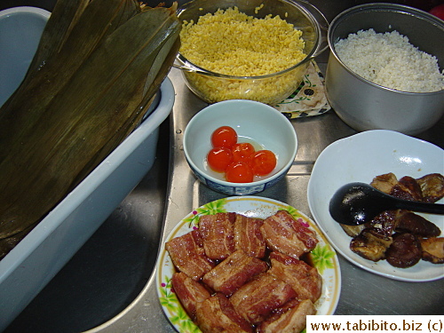 Zongzi mise en place.Fillings include soaked and seasoned mung beans, glutinous rice, salted egg yolks, marinated dried shiitake and lean pork belly