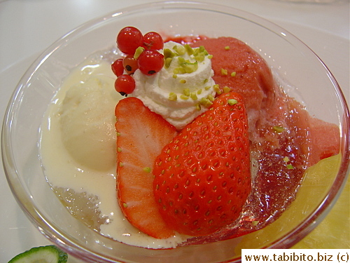 The bowl contains a scoop of vanilla icecream, raspberry sorbet afloat a pool of finely chopped jelly thing.  The berries on top were super sweet
