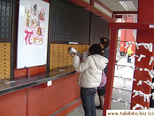 People shake the tin and a ball with a number will fall out, they then get the slip corresponding to the number to read the fate of the day.  You're supposed to drop a dollar in the collection box, but I wonder how many visitors actually do that?