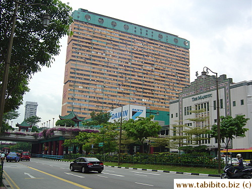 A skinny apartment building stands amidst pavilions and a Chinese opera theatre