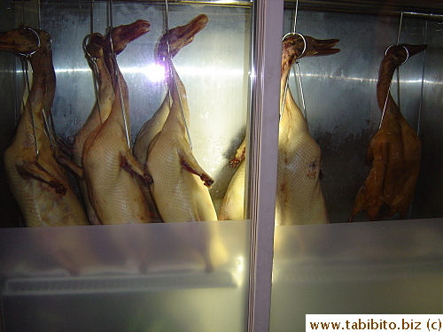 Two fridges just inside the entrance of the restaurant; one has uncooked ducks