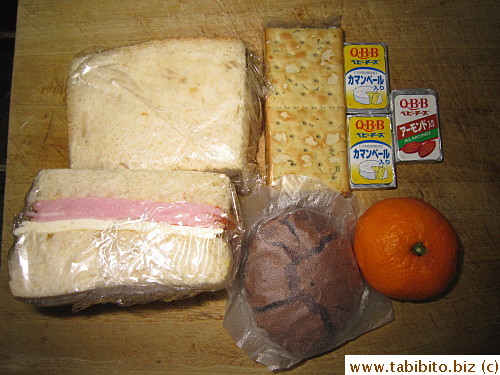Ham and cheese sandwich, rosemary crackers, cheeses, chocolate cookies, mandarin
