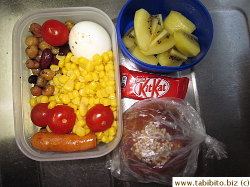 Sausages, beans and corn, soft-boiled egg, cherry tomatoes, kiwi, KitKat, raisin roll